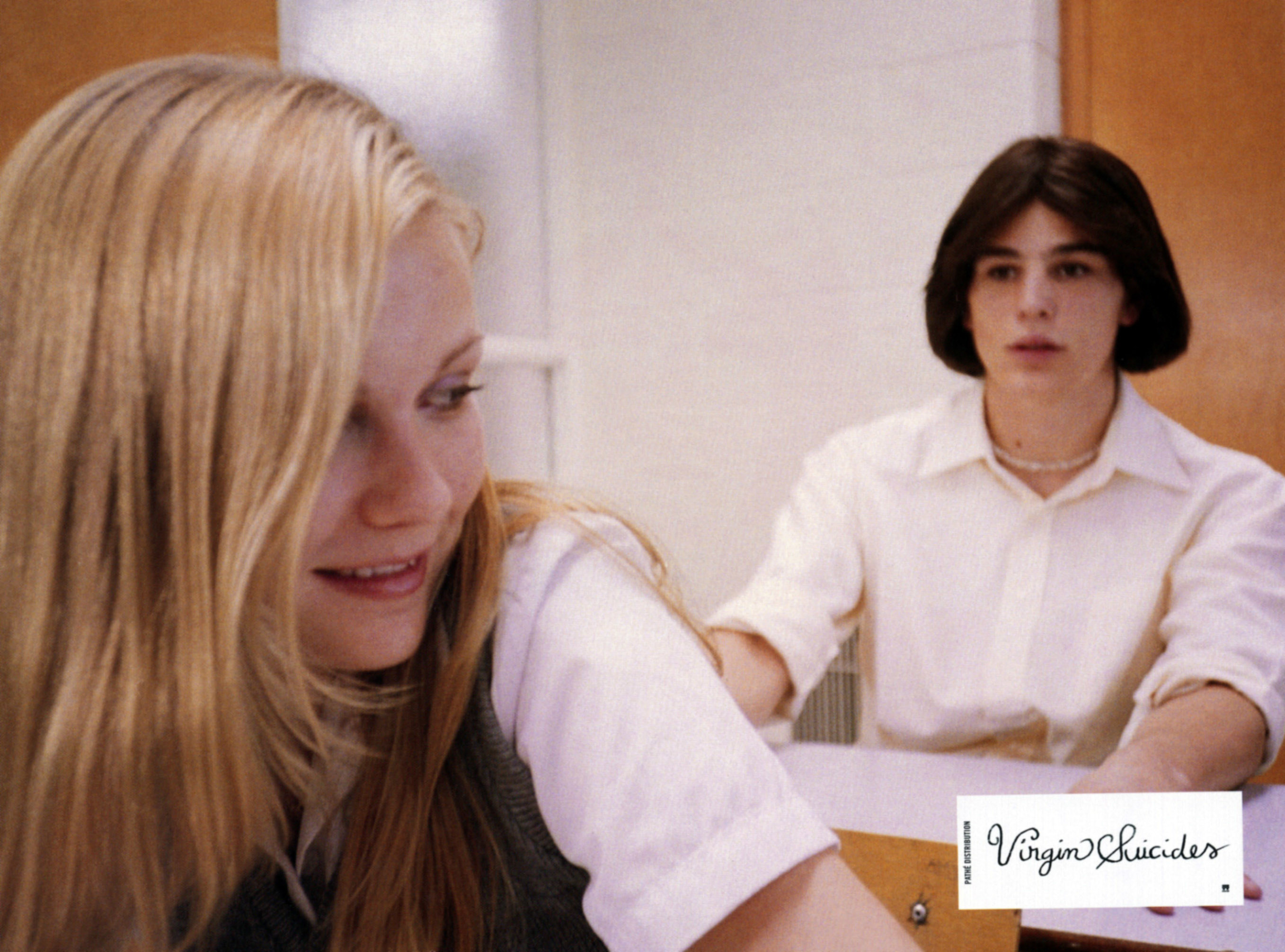 Dunst looks over her shoulder at Josh Hartnett while sitting at a desk