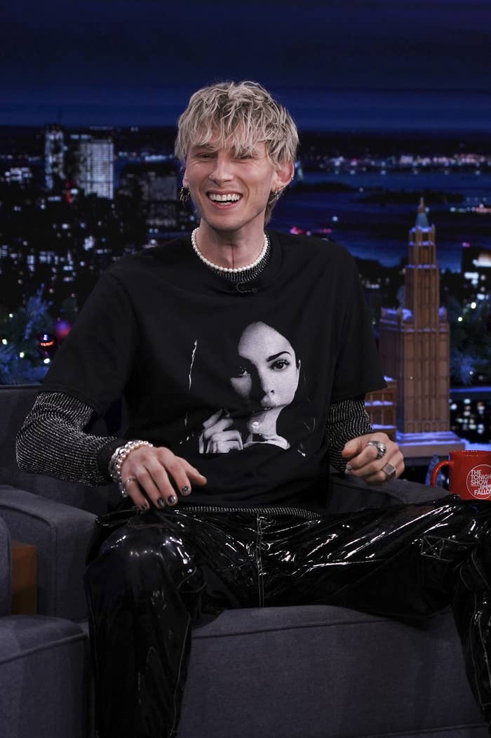 MGK smiling during a late-night TV interview while wearing a t-shirt with Megan&#x27;s face on it