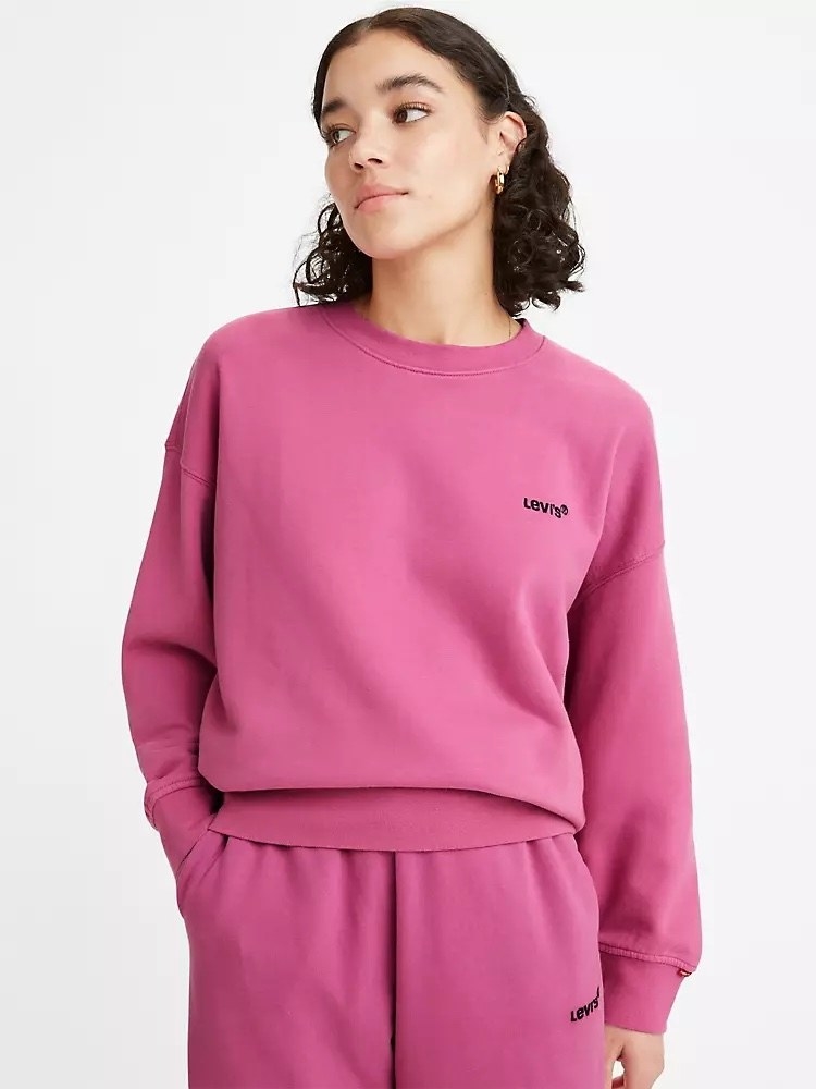 Model wearing bright pink sweatershirt and matching pants with black detailing