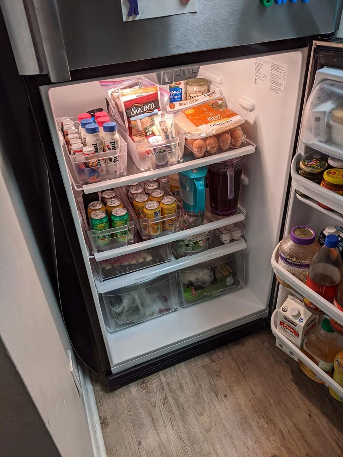 reviewer&#x27;s fridge filled with several labeled pantry organizers
