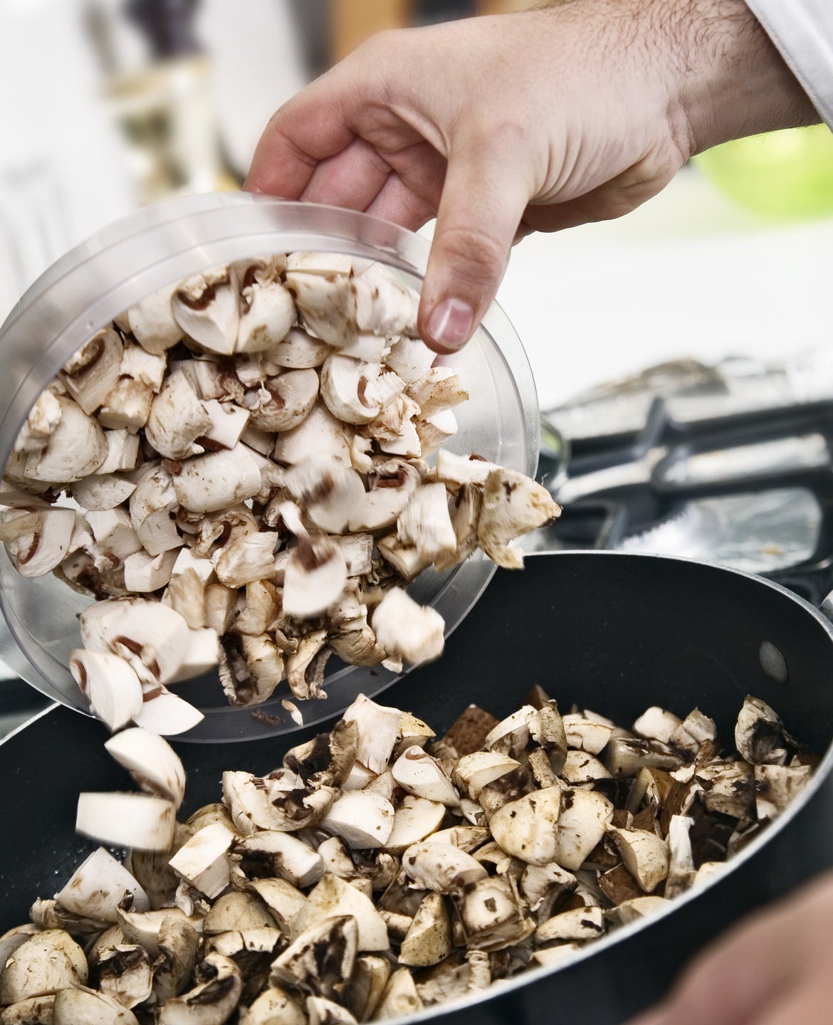 Mushrooms being poured into a pan.