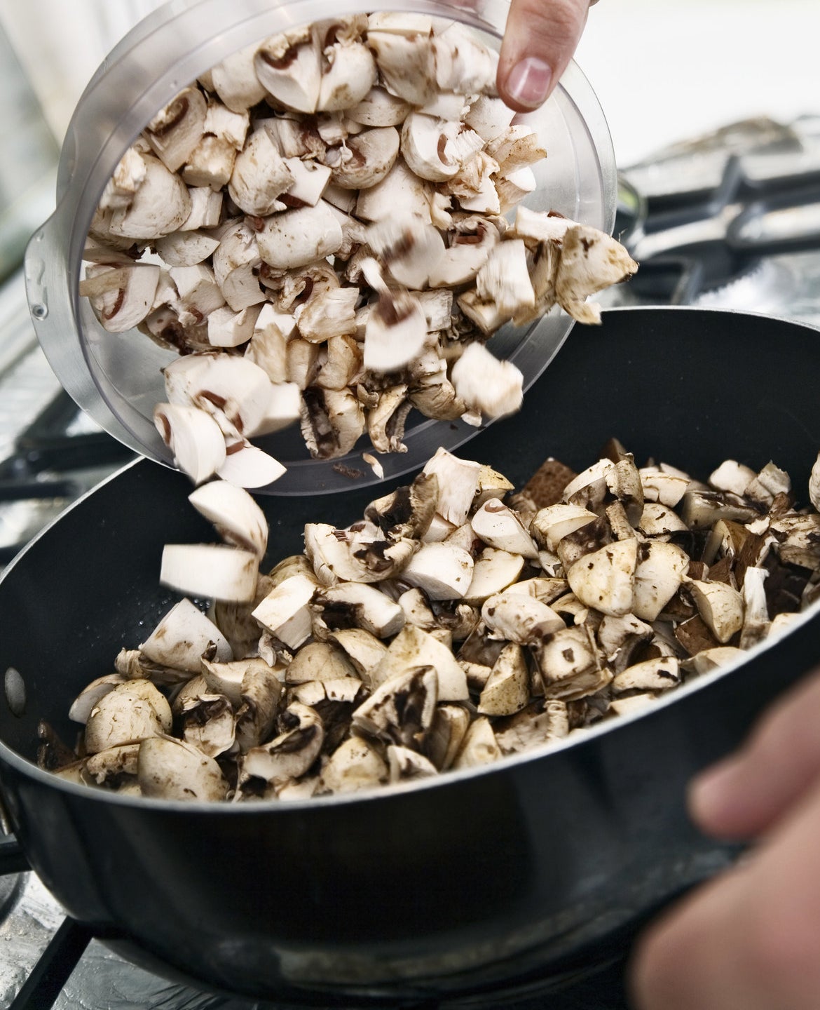 Mushrooms being poured into a pan.