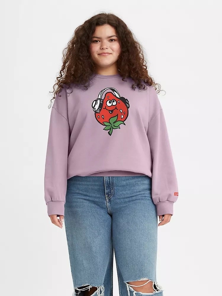 Model wearing purple sweatshirt with strawberry and headphone and jeans