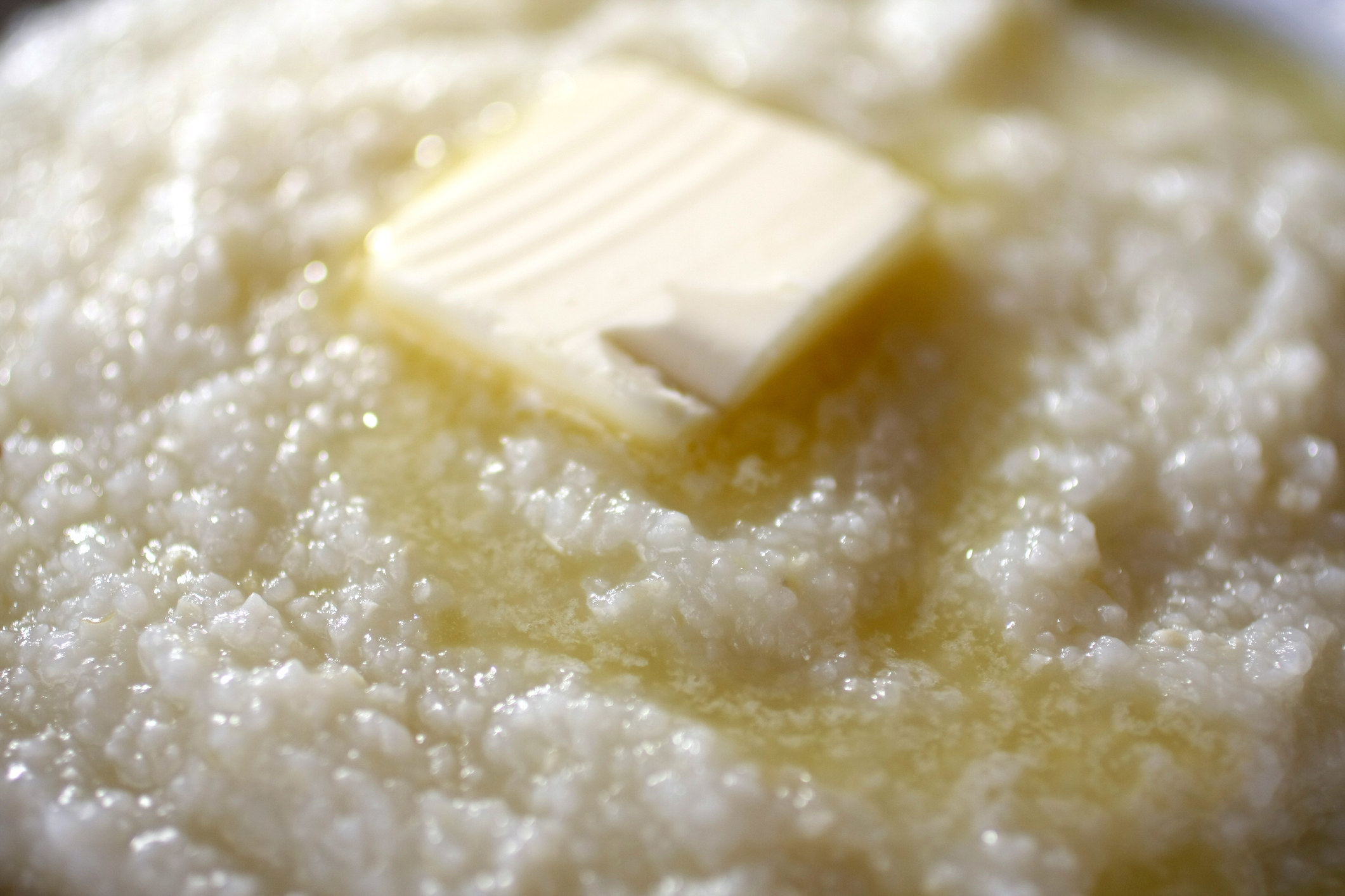 Close-up of bowl of grits topped with butter.