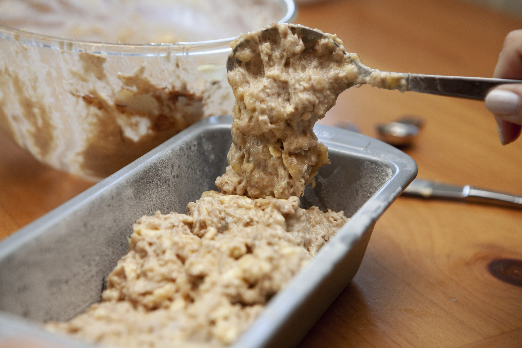 Banana bread mixture being emptied into a baking tray.