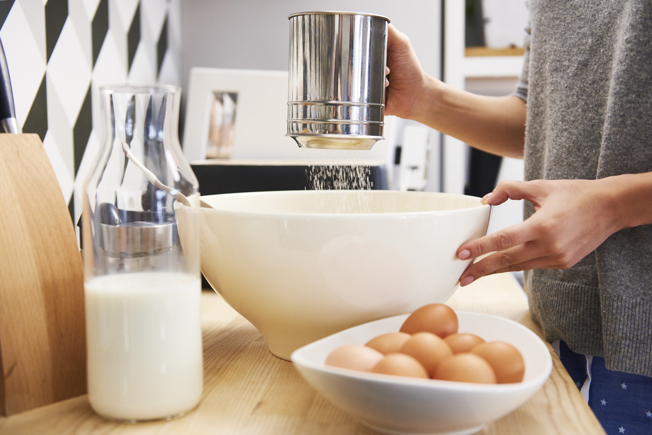 Young woman preparing batter for pancakes.