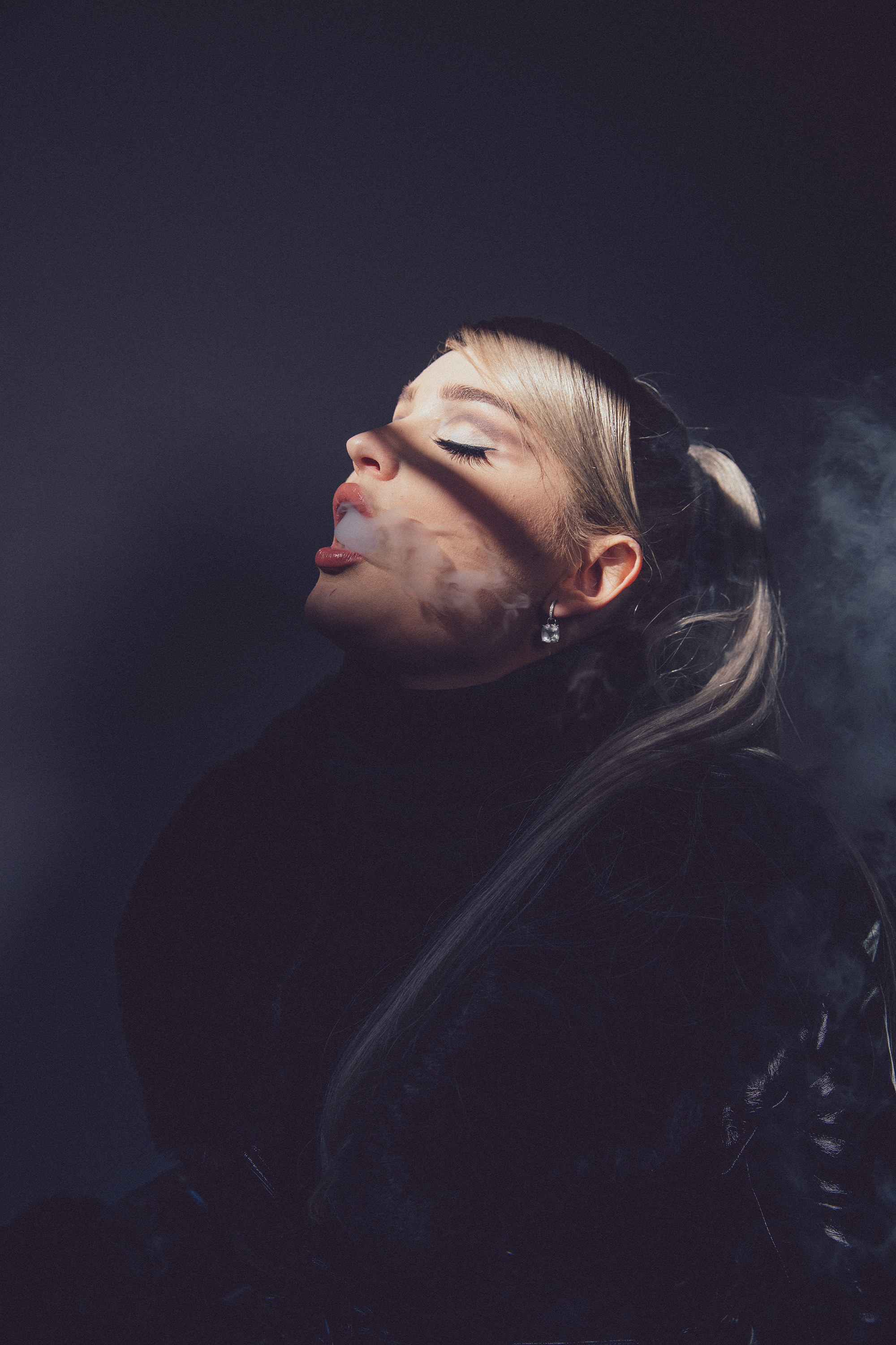 Kim Petras blowing smoke in a portrait