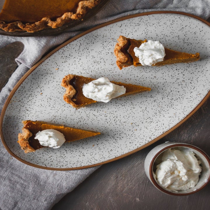 Overhead view of the oval platter holding three slices of pie and the ramekin filled with whipped cream
