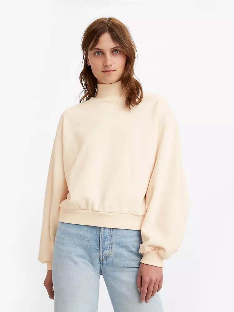 Model wearing cream sweatshirt with jeans