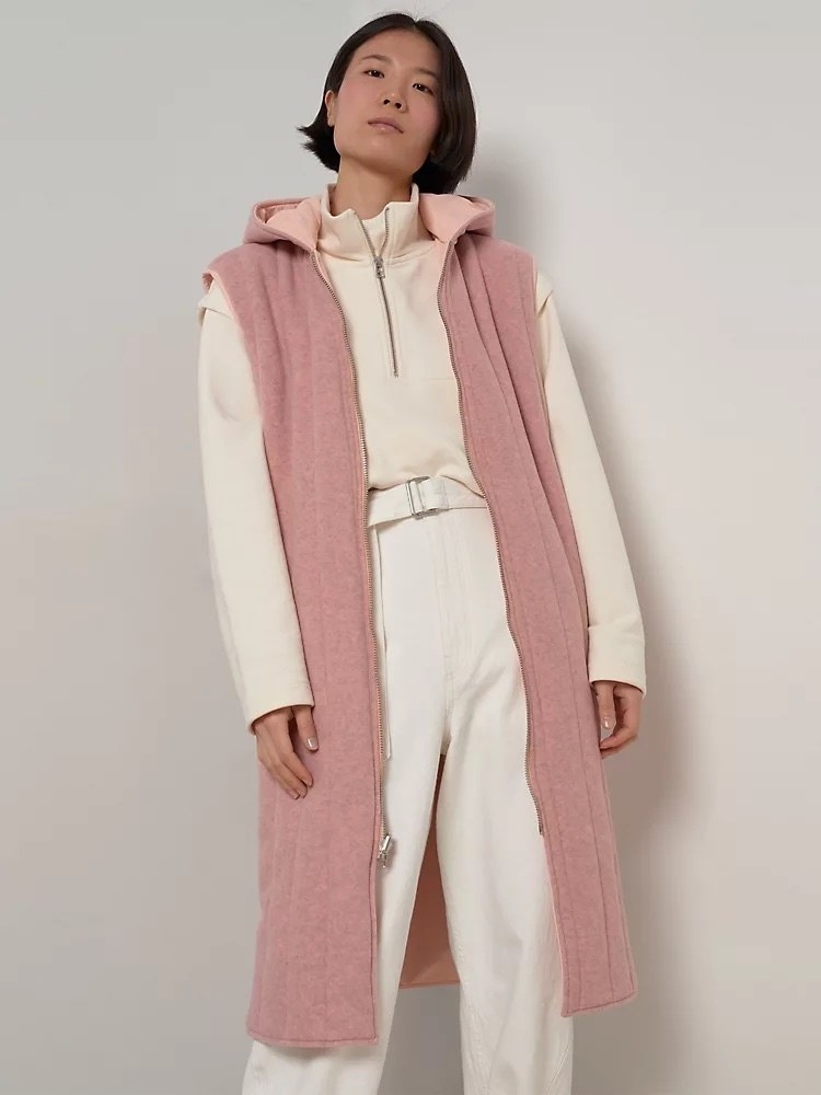 Model wearing white outfit with pink long vest over