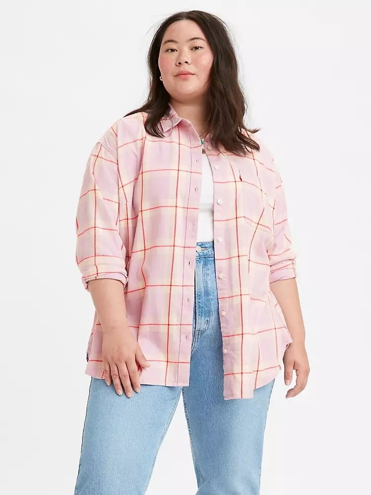 Model wearing pink and red flannel over white shirt and jeans