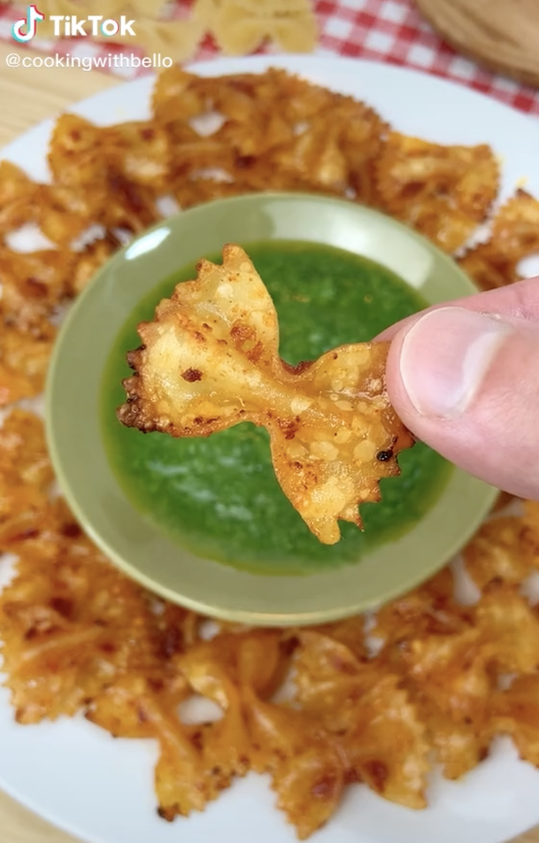 A person holding up a bowtie pasta chip 