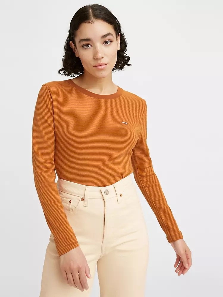 Model wearing orange striped tee and white pants