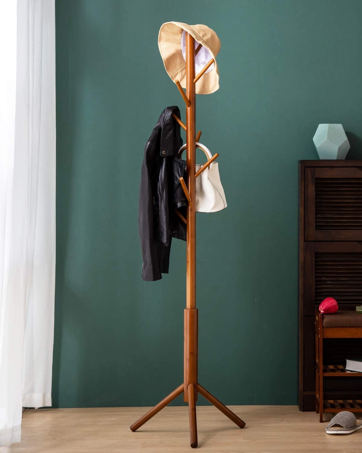 The wood coatrack holding a jacket, bag, and hat