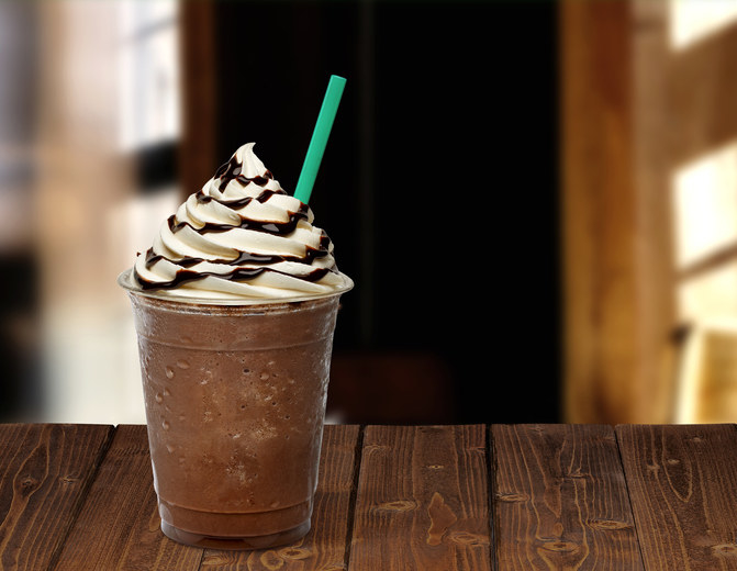 Frappuccino in takeaway cup on wooden table isolated on black