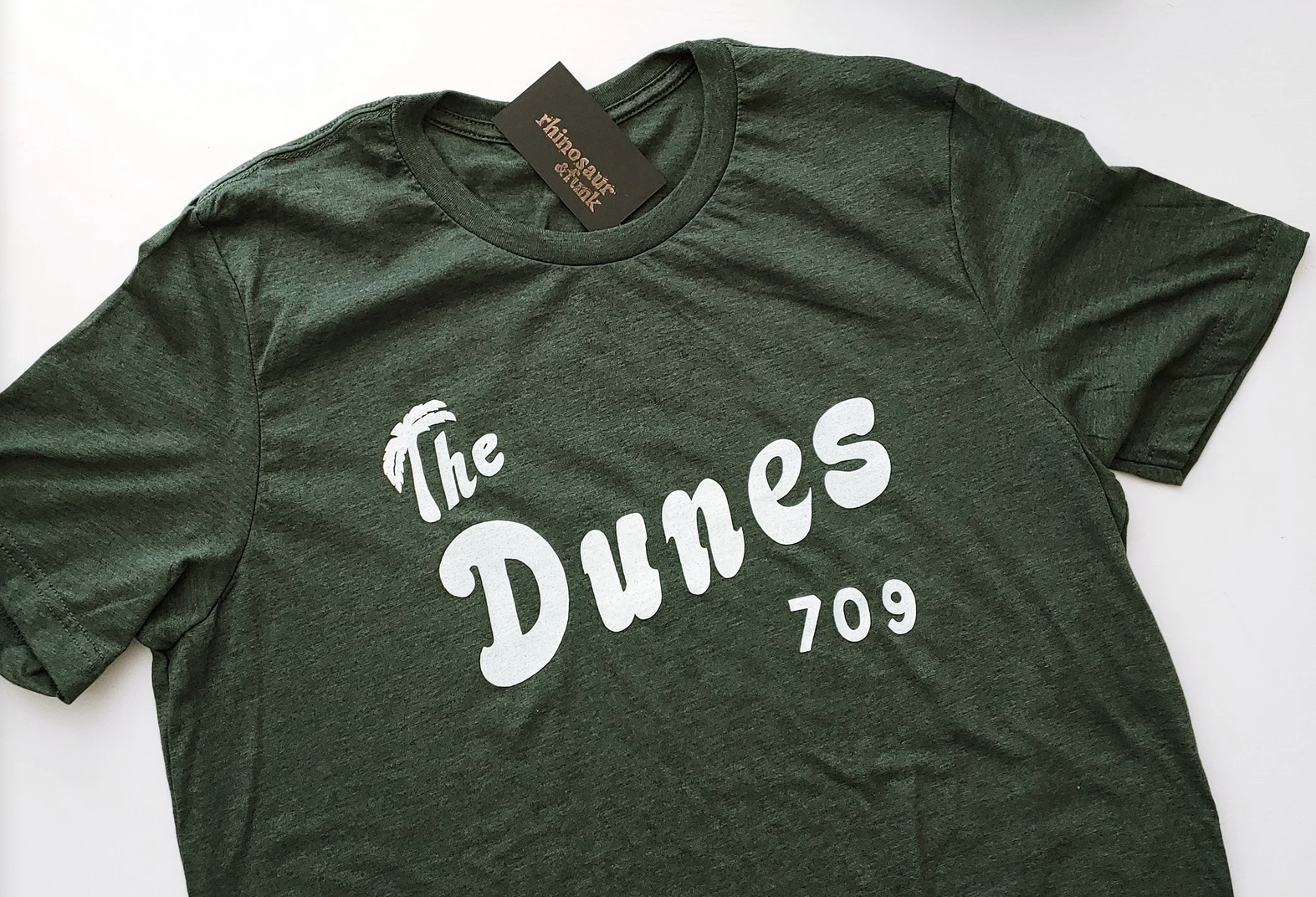 A soft green t shirt that has the Dunes 709 printed on the front in the same font as the building from the show