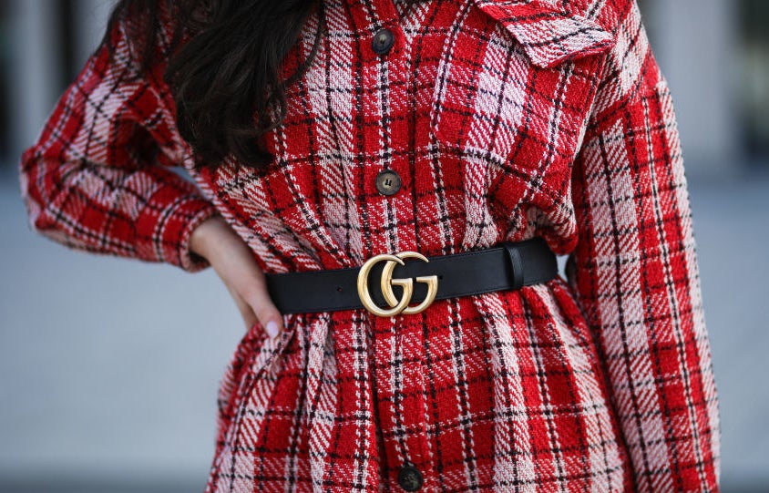 A person wearing a plaid coat with a Gucci belt with the GG logo