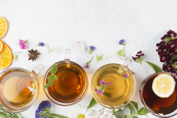 Various herbal teas surrounded by flowers