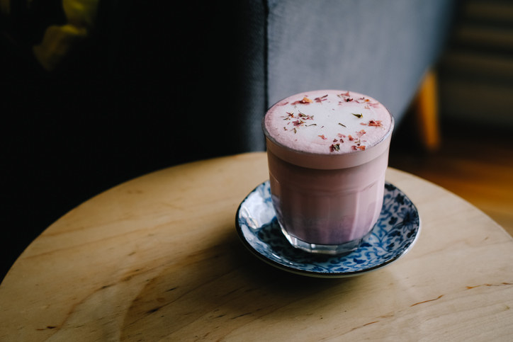 Rose beetroot latte with vegan coconut milk on wooden table at hipster coffee shop