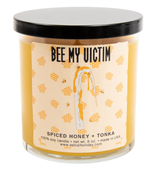 A soy candle in a jar with Candyman&#x27;s hook covered in honey on the label made from spiced honey and tonka