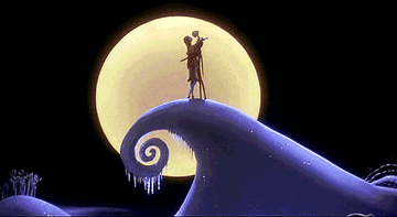 Two figures kiss on a swirling snow ledge in front of the moon