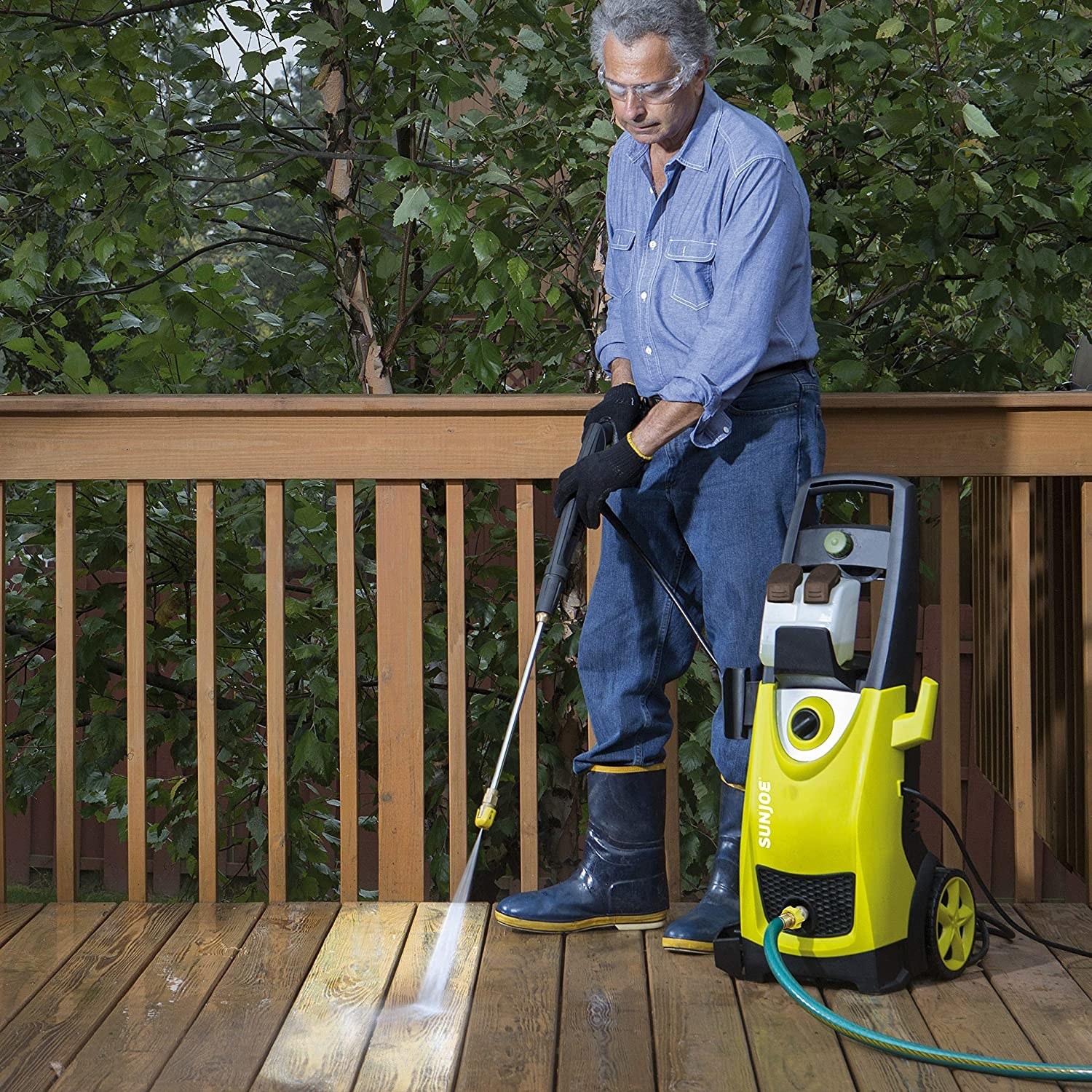 A person using the pressure washer on a deck