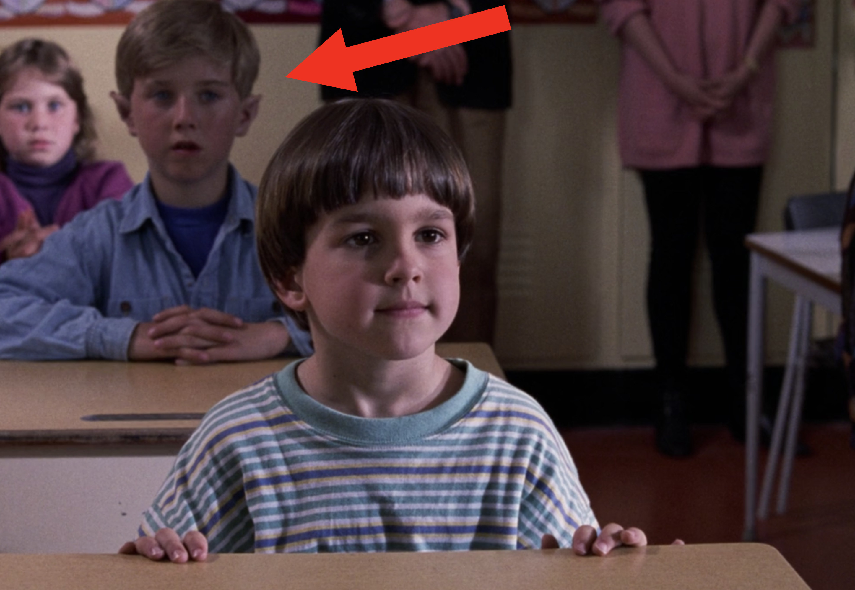 A little boy with pointy ears sitting behind Charlie in class