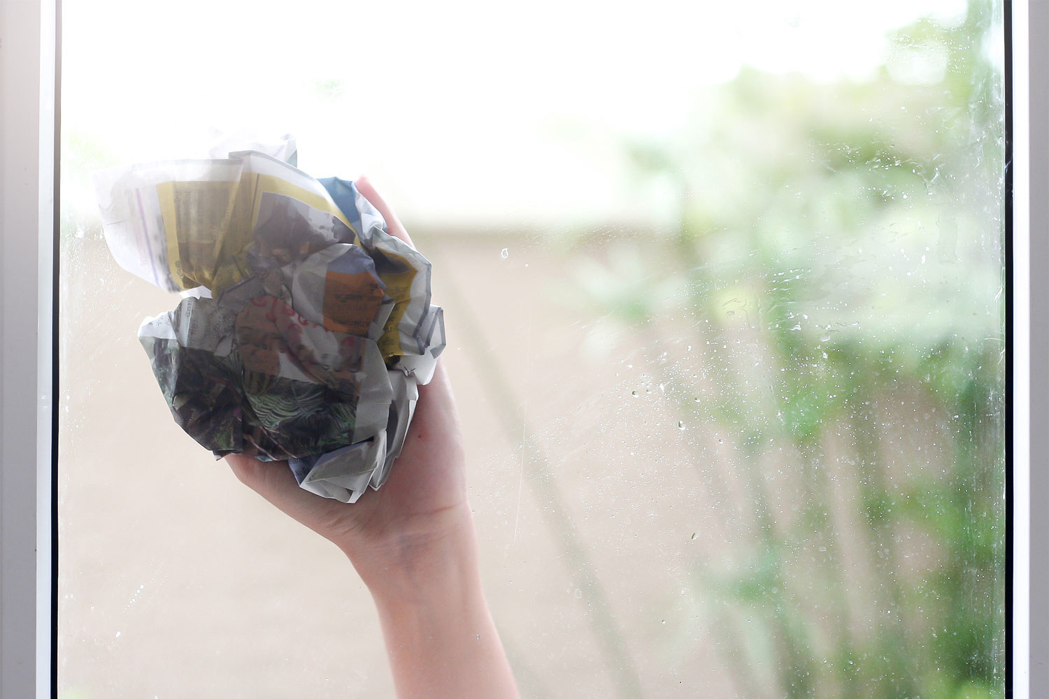 Cleaning a glass window with a ball of newspaper