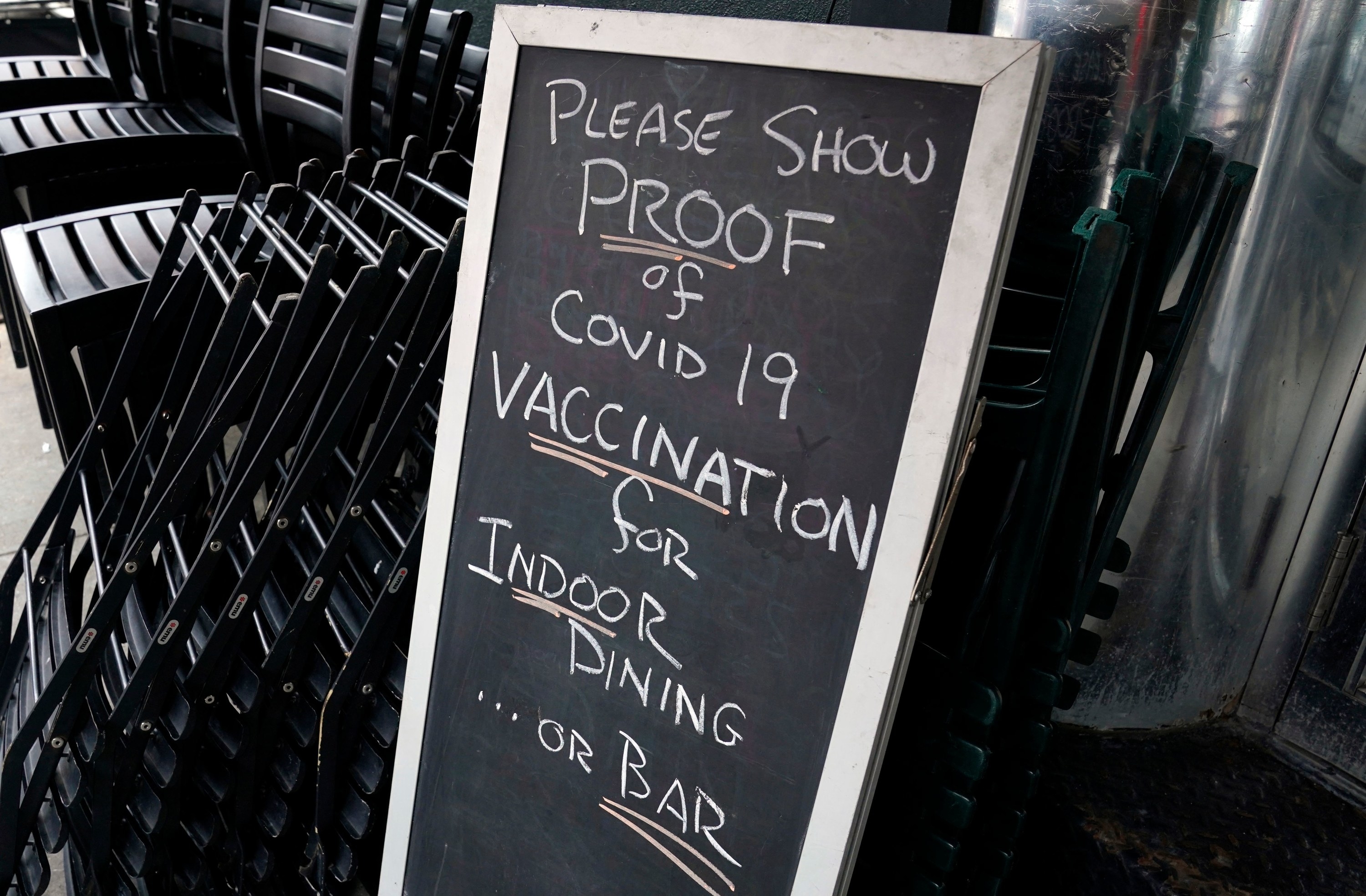 Sign outside restaurant with text: &quot;Please show proof of COVID-19 vaccination for indoor dining or bar&quot;