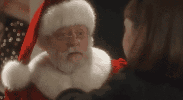 GIF of a little girl pulling on Santa&#x27;s beard and smiling when it doesn&#x27;t come off