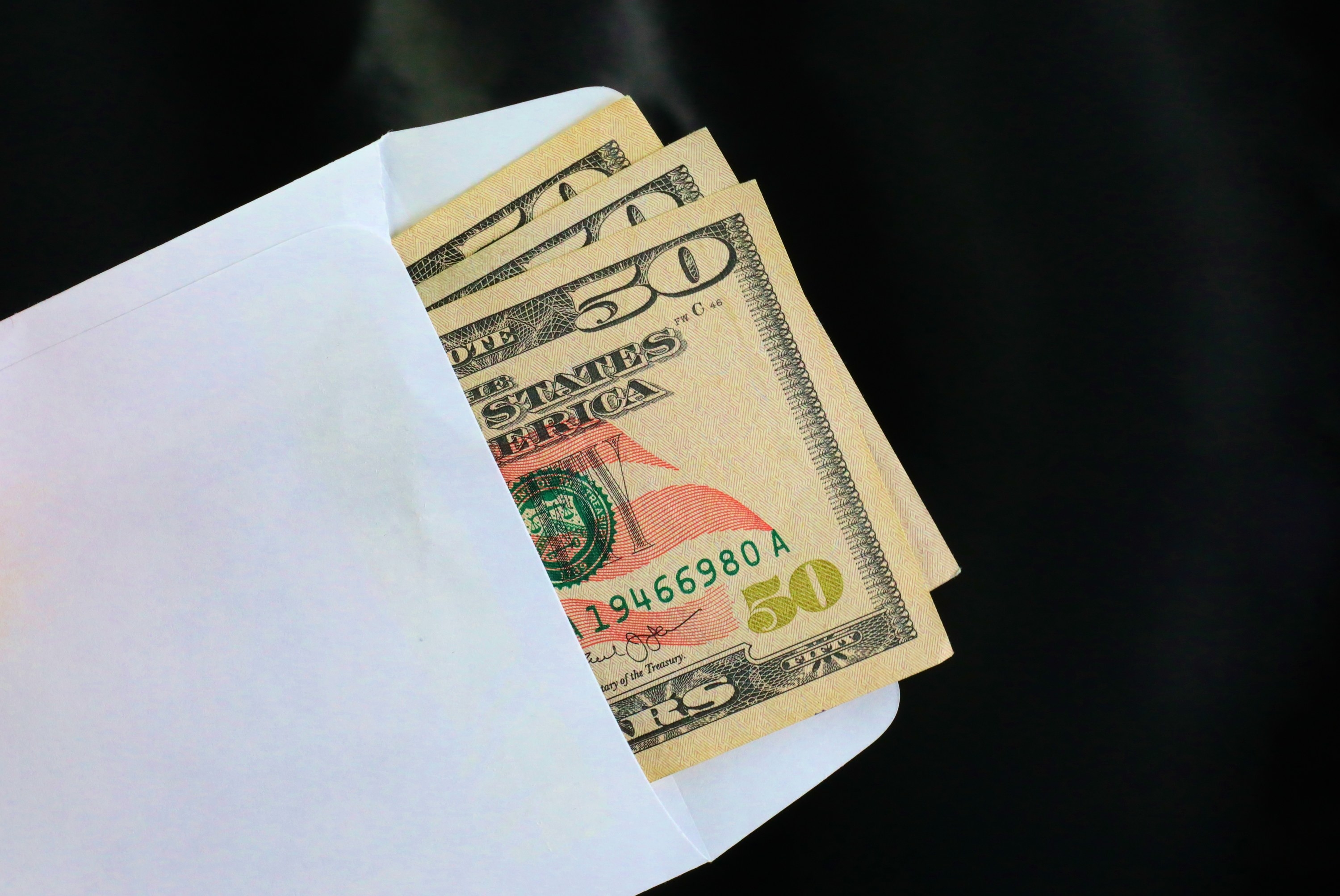 Three $50 bills in a white envelope.