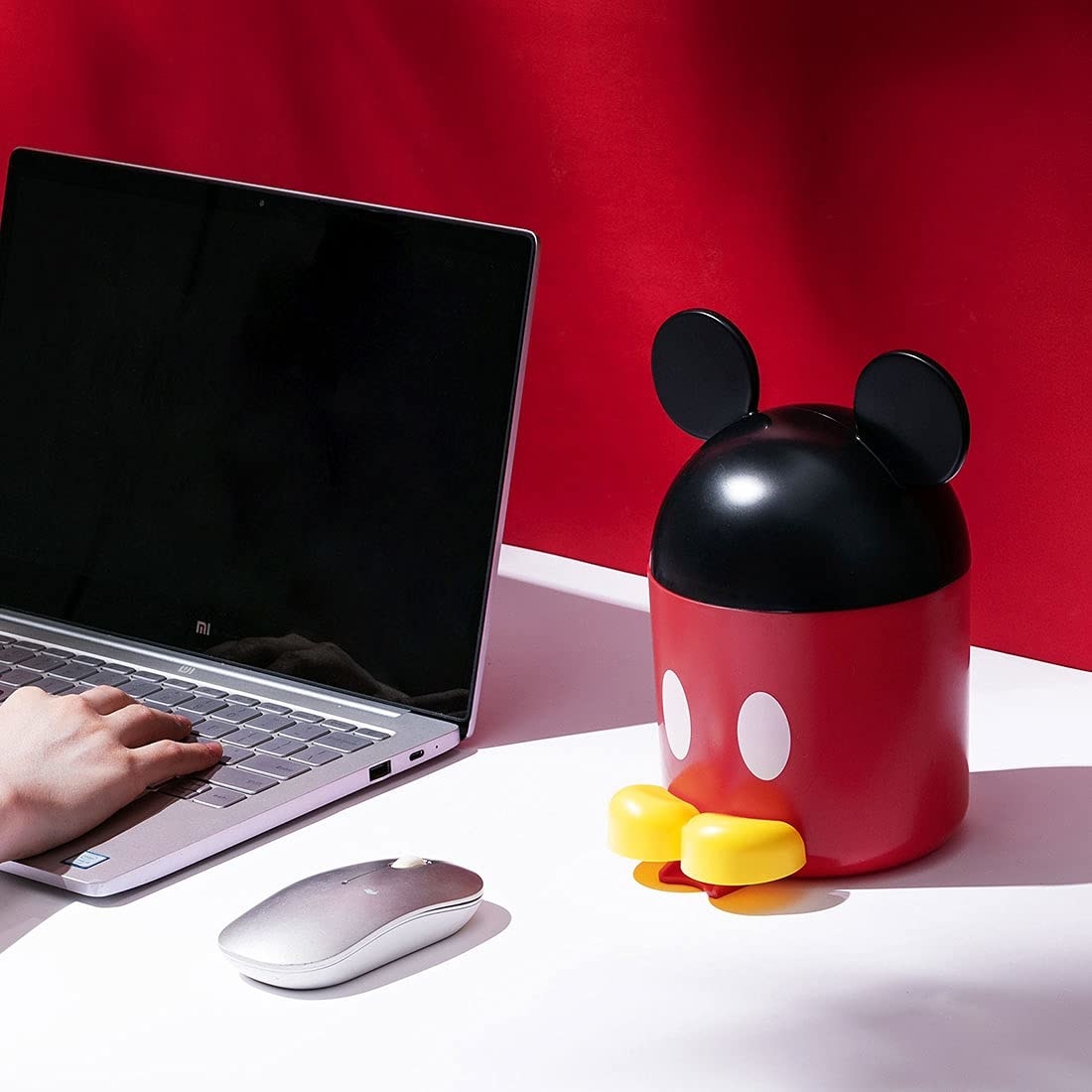 A Mickey Mouse storage container next to a keyboard and a mouse