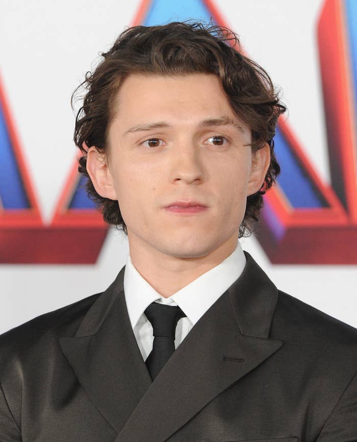 Tom Holland looks off to the side while wearing a suit