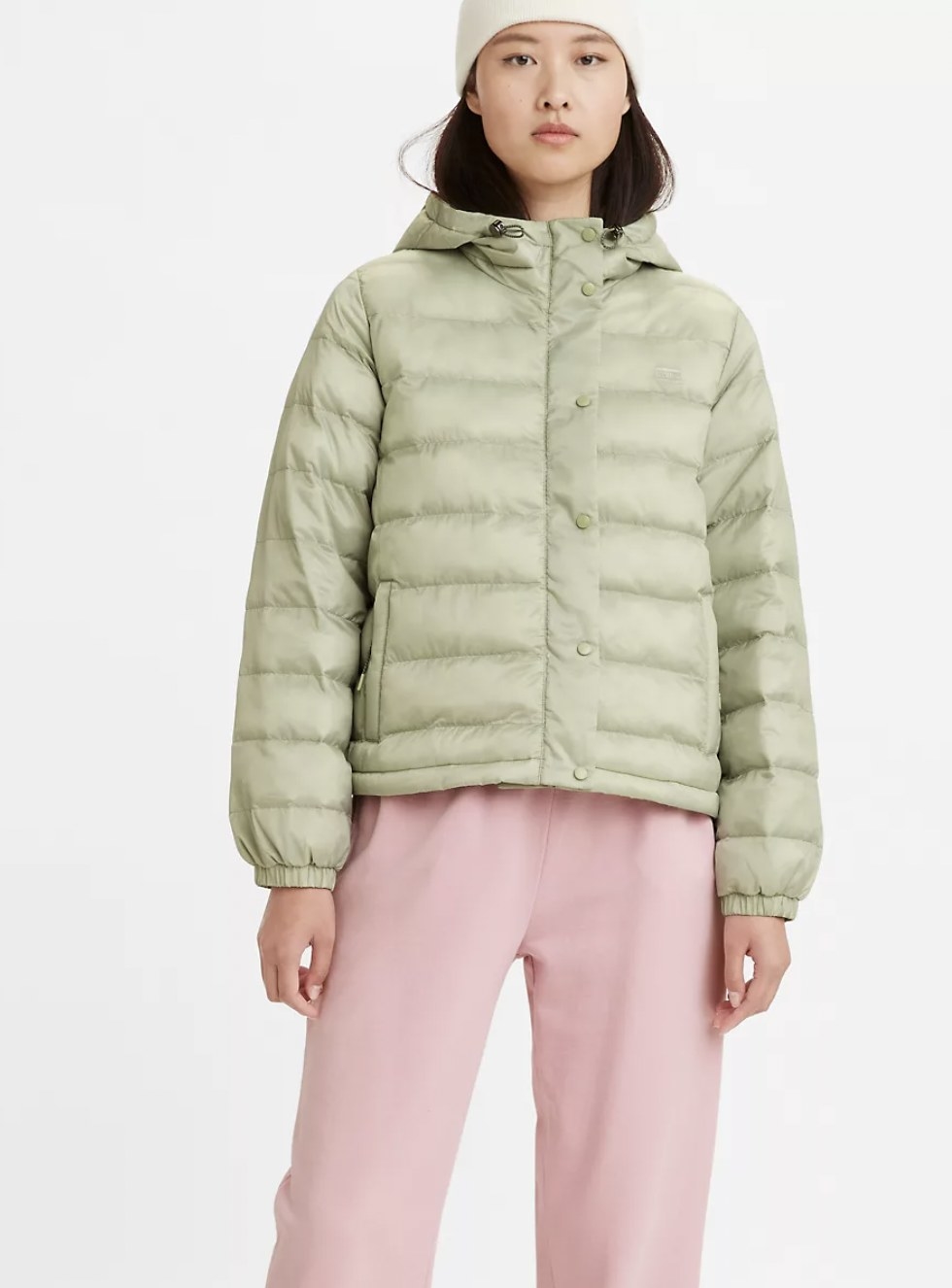 Model wearing the light green puffy jacket featuring button-closures, side pockets and hood
