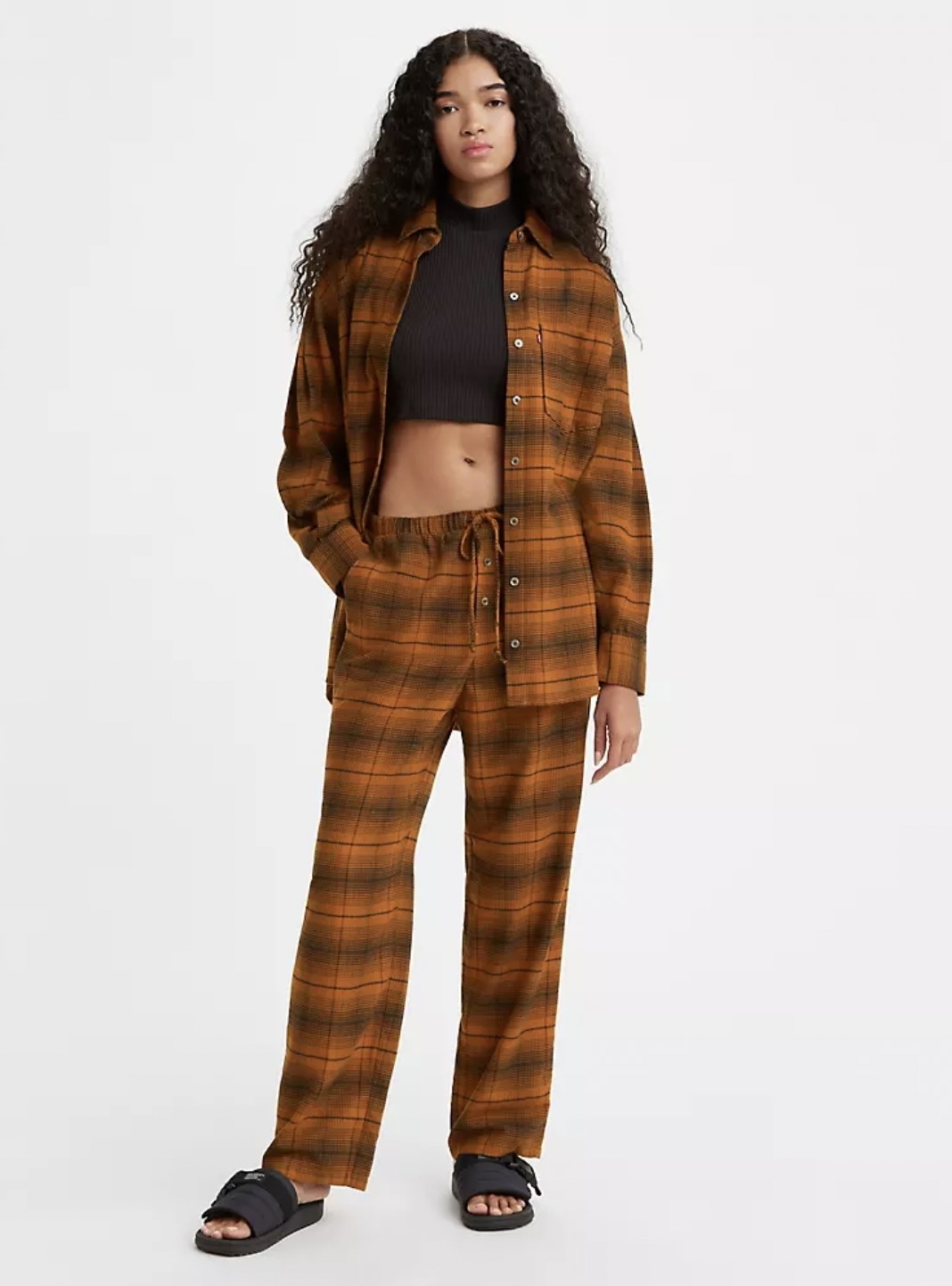 Model wearing the rust-colored plaid lounge pants with crop top and matching flannel