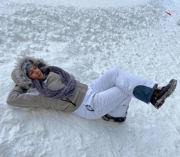 Reviewer wearing the white snow pants while laying in the snow