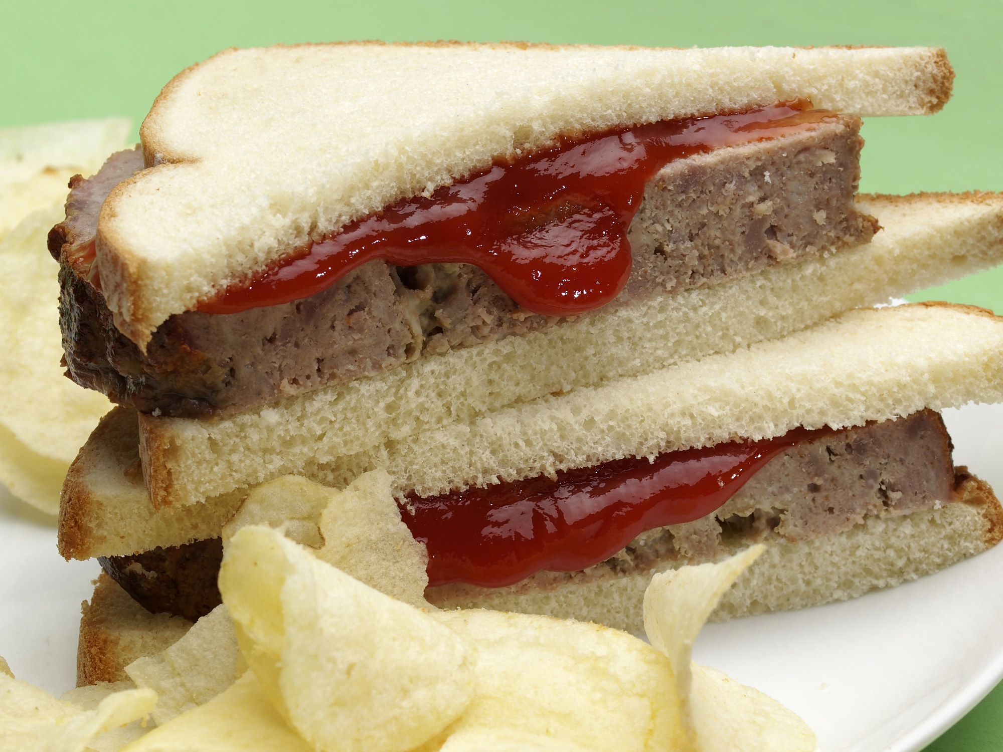 Meatloaf on white bread with ketchup.