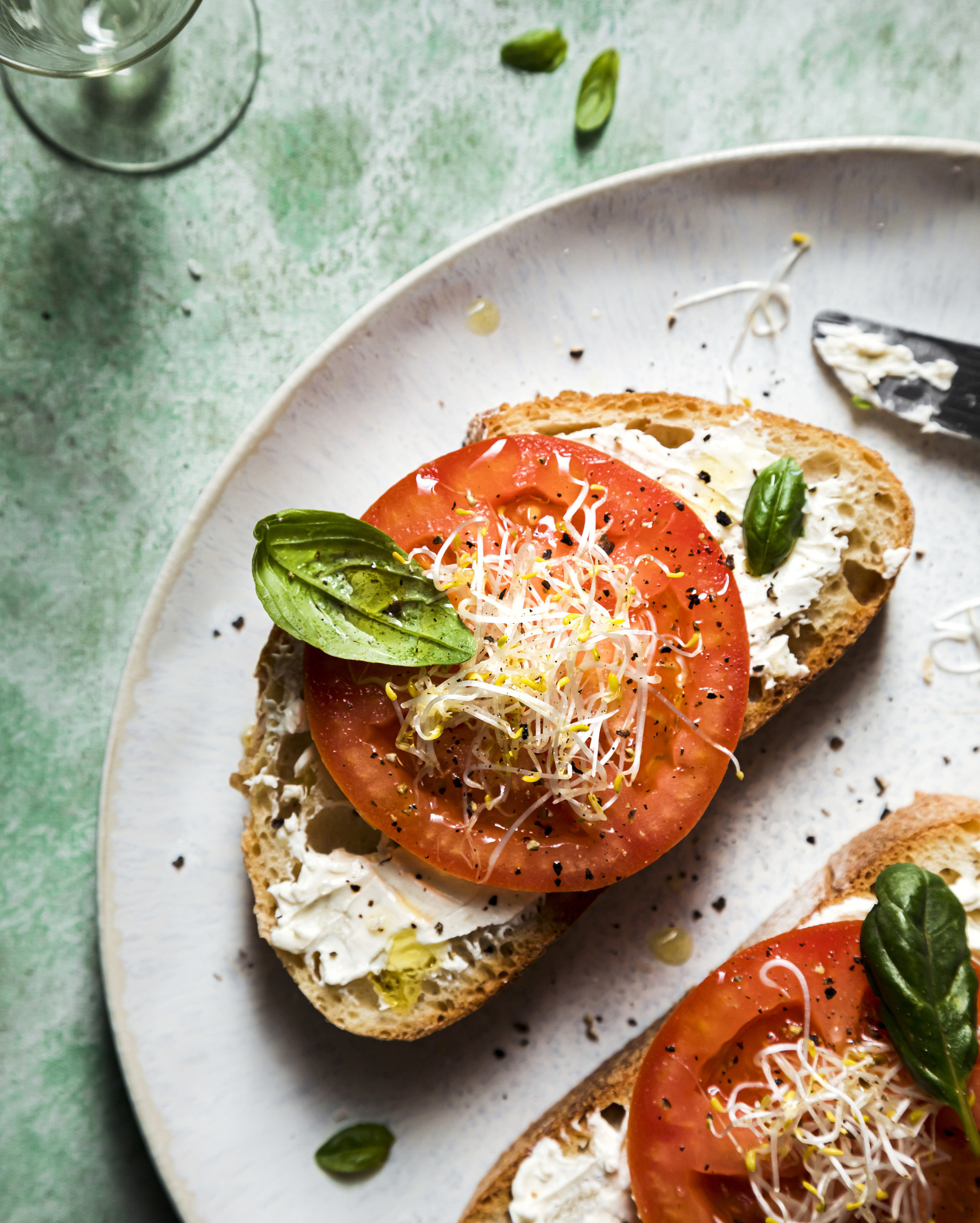 Open-faced tomato sandwich with mayonnaise and basil.