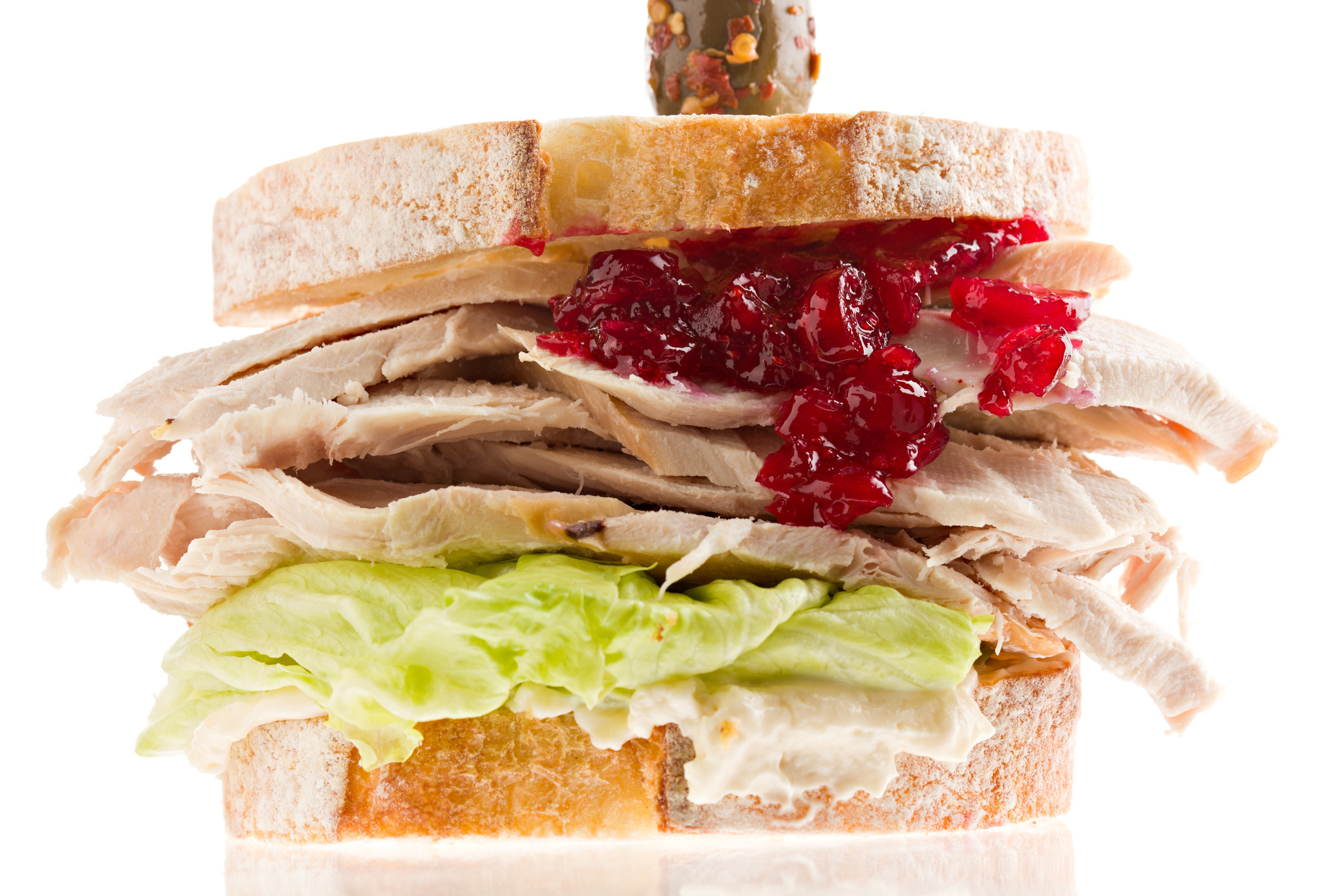 A turkey sandwich with lettuce, cranberry sauce, and mayo.