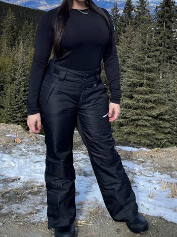 Reviewer wearing the black snow pants on a mountain