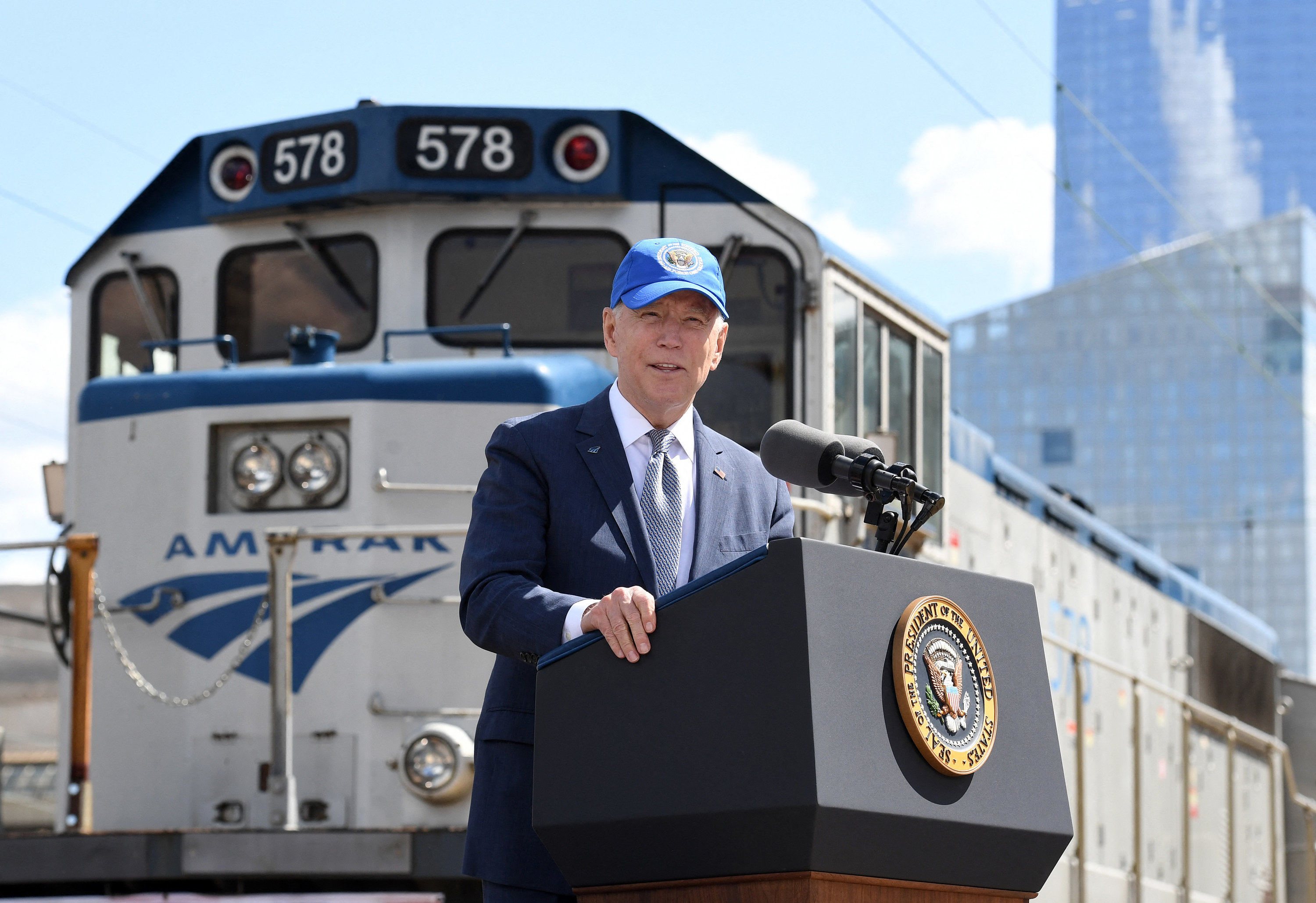 Biden speaks at a lectern in front of an Amtrak train