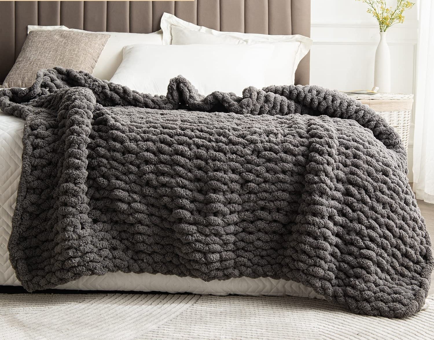 A chunky knit blanket on the end of a bed