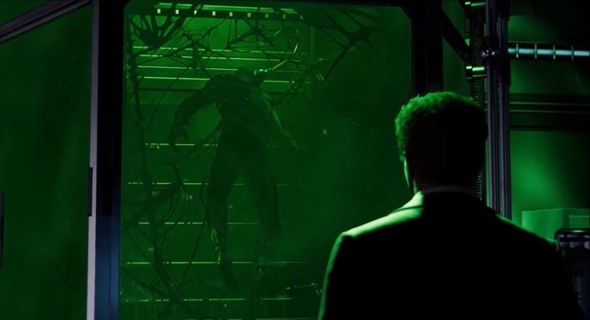 Harry Osborn floating in a green tank with the Venom symbiote attached to him with his father, Norman, watching him, in &quot;Marvel&#x27;s Spider-Man&quot;