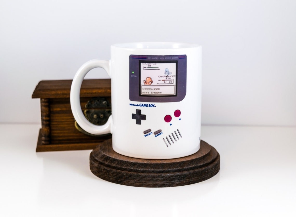 a white mug that looks like an old game boy with pokemon on the screen