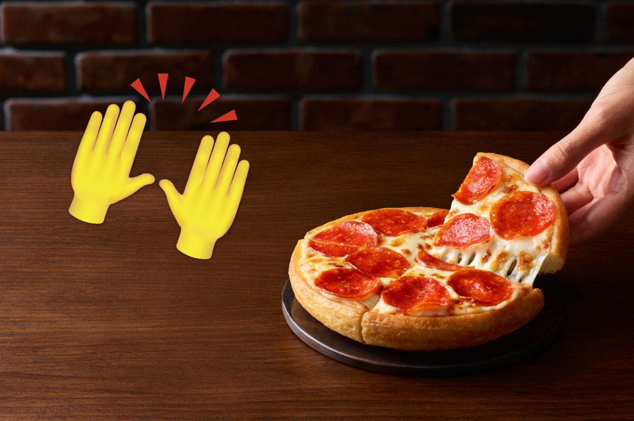A Personal Pan Pizza with a hand coming in from the right side of frame to pull a slice away. To the left of the Personal Pan Pizza is a raised hand emoji