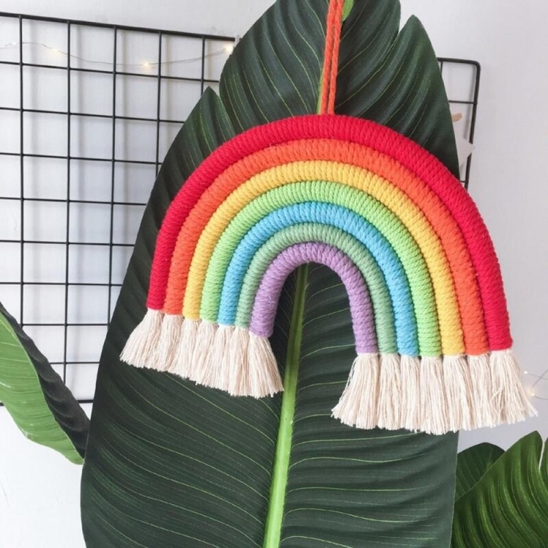 woven rainbow hanging in front of a plant