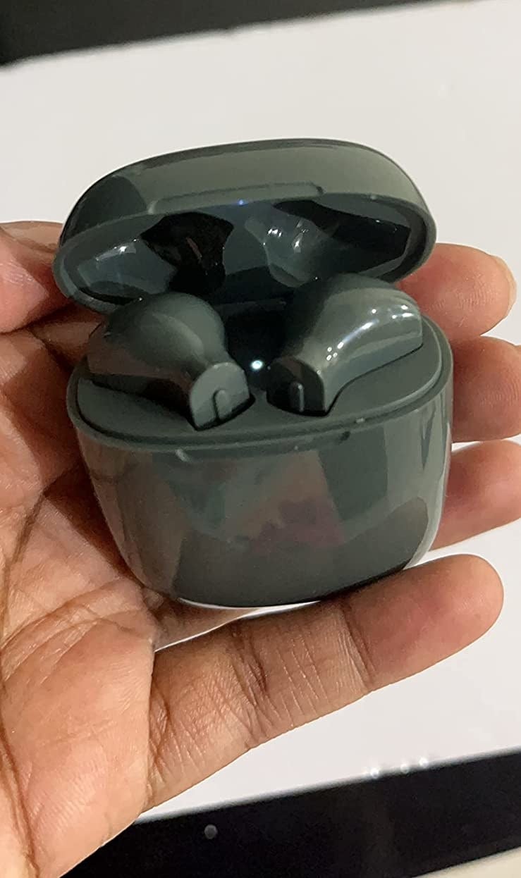 Reviewer holding green wireless earbuds in charging case