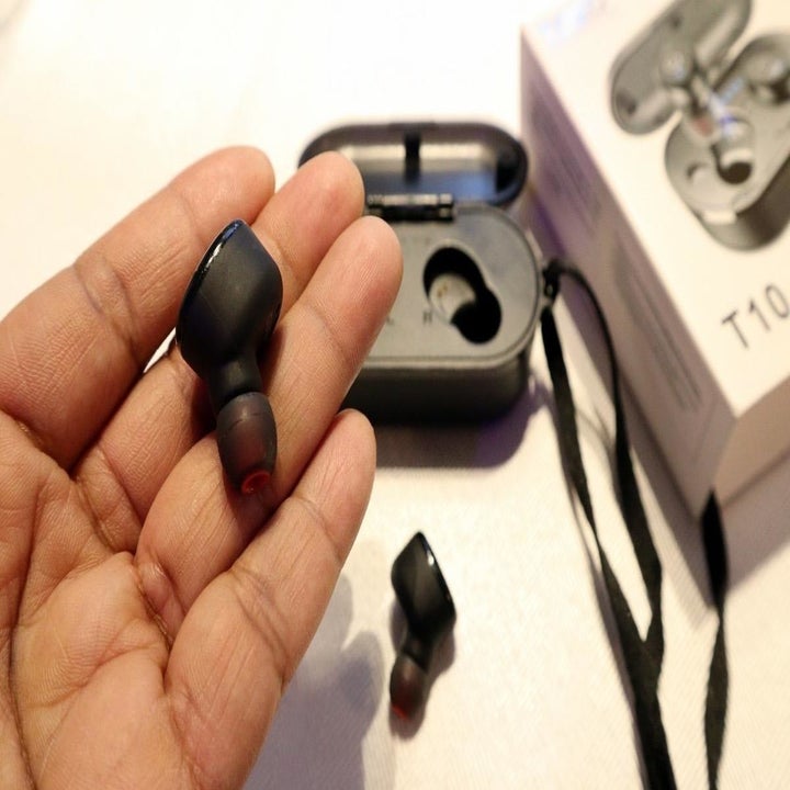 Reviewer holding earbuds in hand