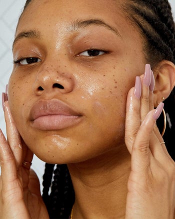 Model applies the Fenty Skin moisturizer above to cheeks and other areas of face