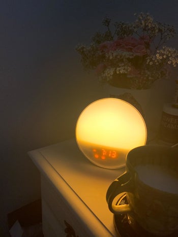 Reviewer photo of the same lamp turned on with a warm yellow hue